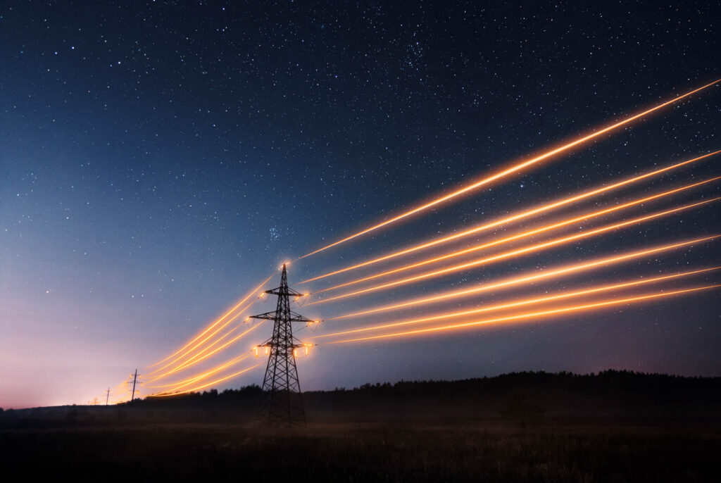 Elmaster mod nattehimmel med lysende ledninger imellem for at symbolisere energi