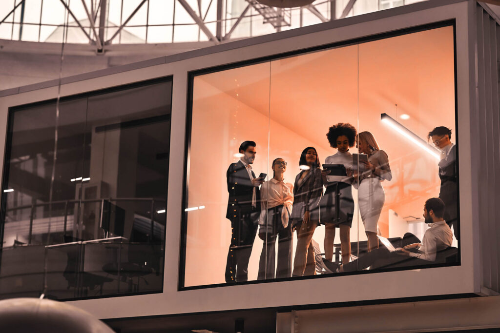 Team members discussing work in a glass-walled meeting room