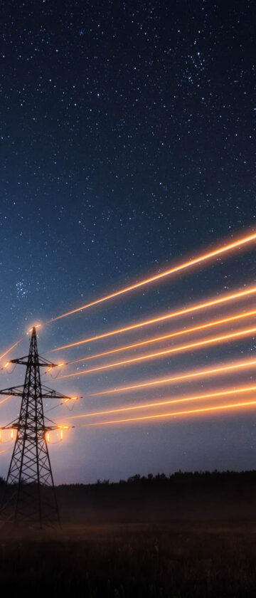 Electricity transmission towers with power lines under a starry night sky