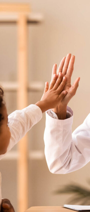 Pediatrician giving a high five to a young patient during a medical consultation