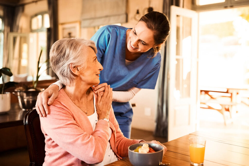 Caregiver providing elderly woman with breakfast